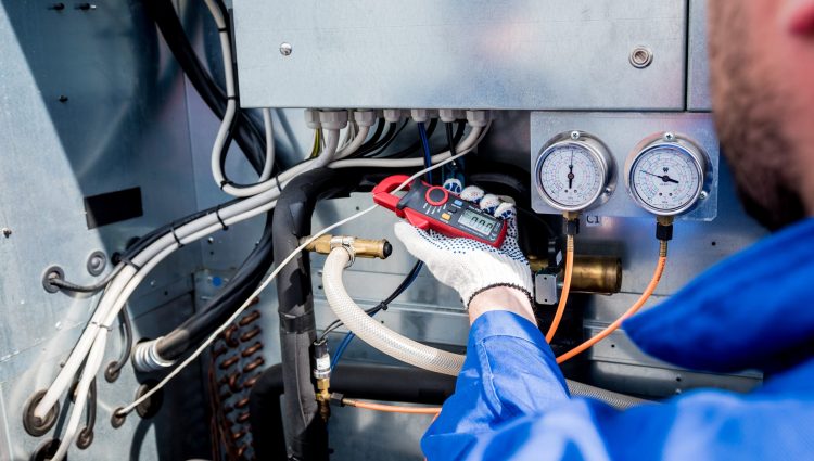 The technician checking power lines of the heat exchanger with current clamps.